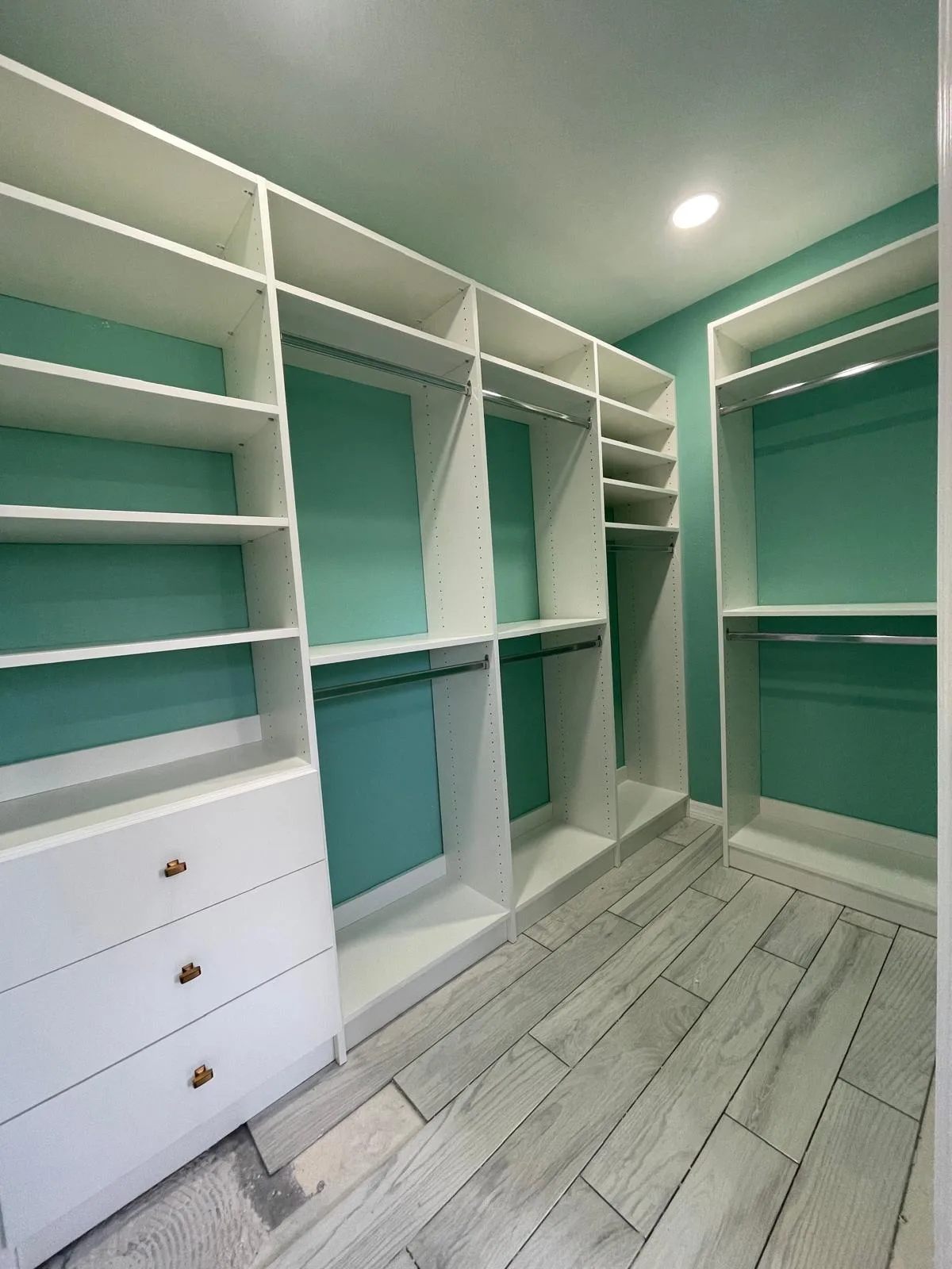 Custom walk-in closet with white shelving on a mint green wall